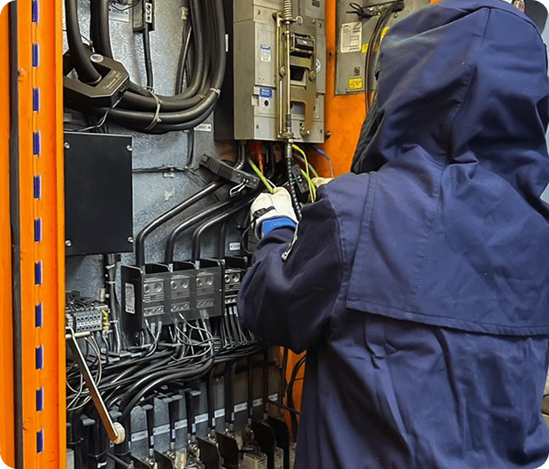 Electrical safety engineer working on a switchboard in arc-flash PPE